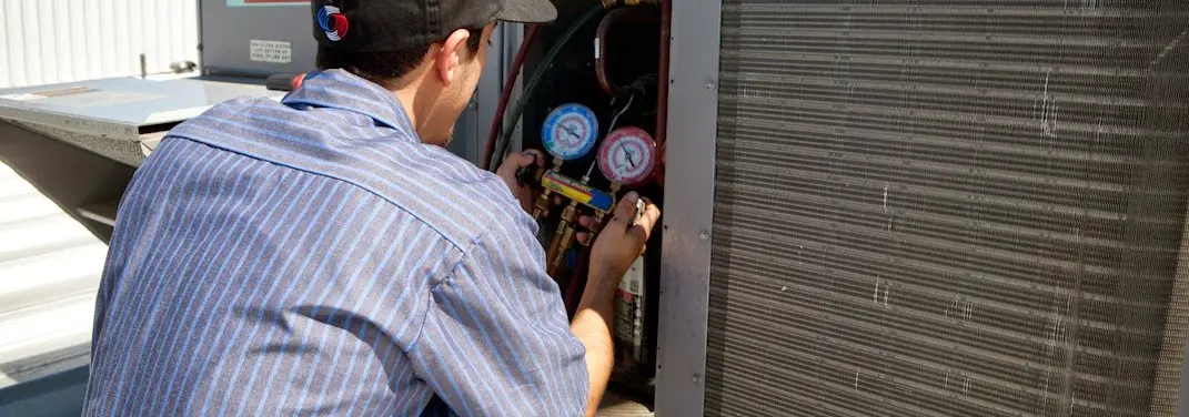 HVAC technician servicing a condenser unit in Bristol